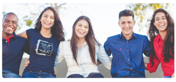 Smiling students sit on a wall with their arms around each other